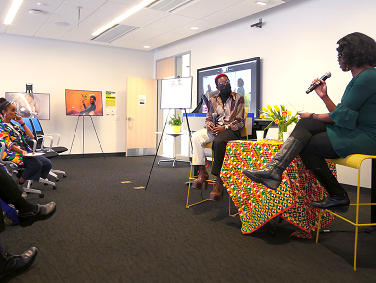 Two masked people engaged in a thoughtful discussion in front of a group
